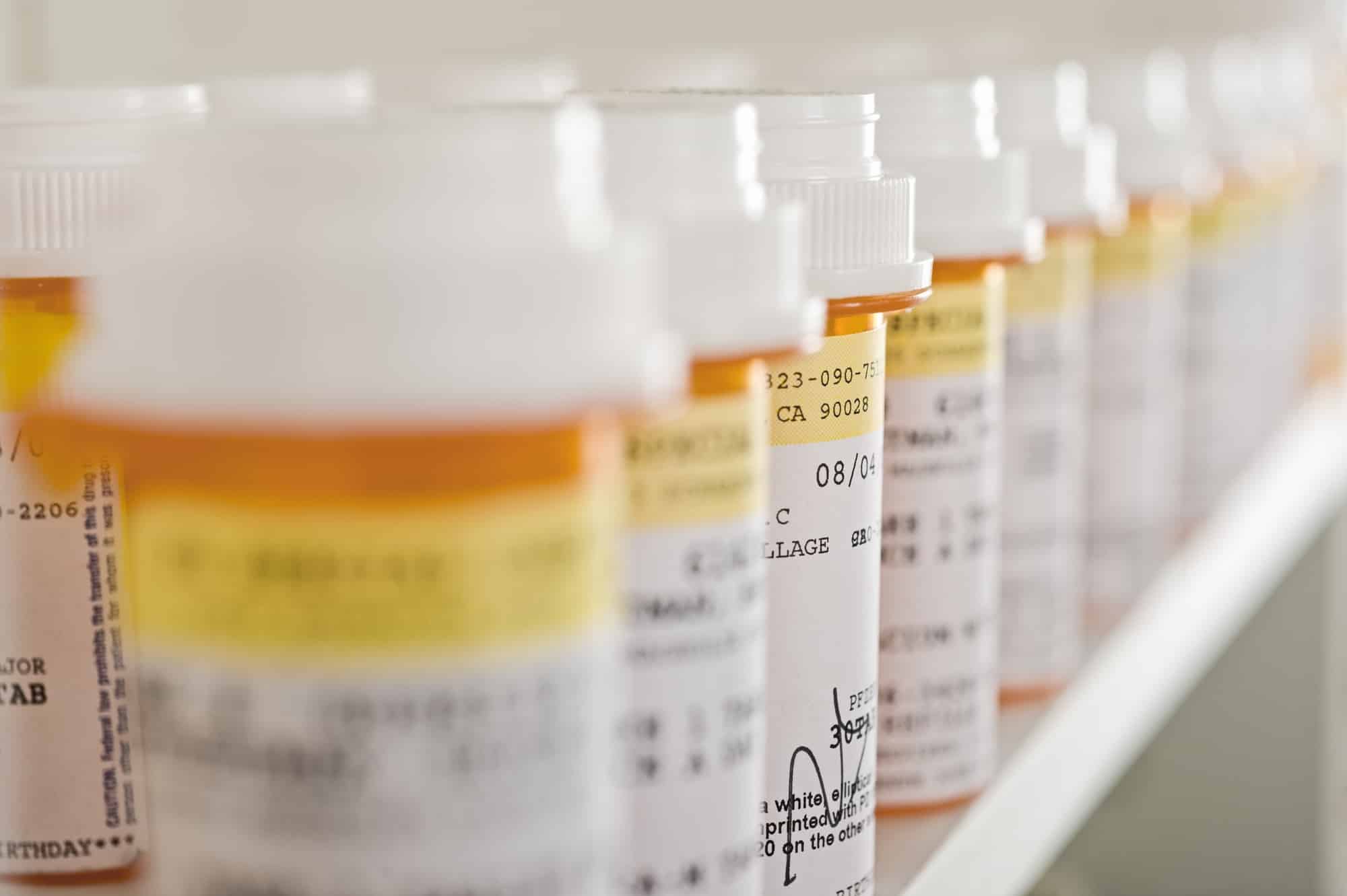Prescription medication bottles lined up on a shelf.
